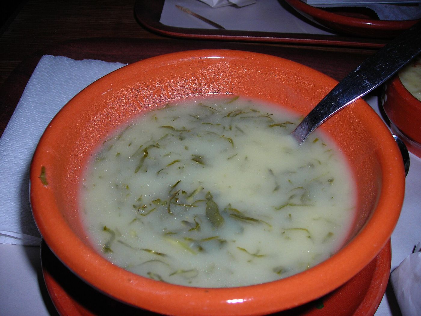 A bowl of caldo verde, the Portuguese soup of potato, onion and thinly sliced kale, finished with olive oil and a slice of chouriço.