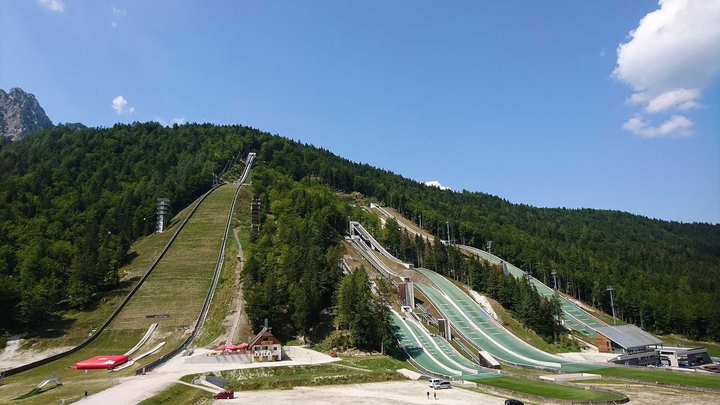 The ski jumping hills at the Planica Nordic Center, where athletes are training on plastic landing mats while the slopes remain bare.